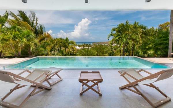 The pool at palm villa is surrounded by tropical greenery and has views to the ocean